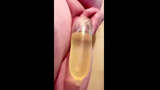 Tiny Tgirl dick fills condom with golden piss
