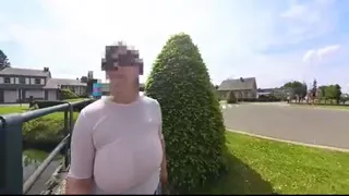 A busty natural milf walking in the street braless with transparent top.